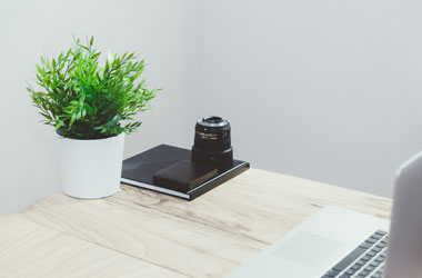 working desk with laptop camera and flowers